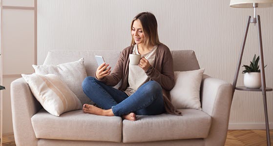 Girl sitting on Sofa looking at the showingtime announcements on a Cell Phone