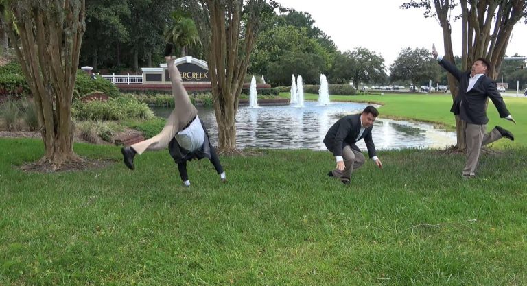 Man doing Cartwheel in the grass outside in front of a fountain